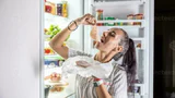 Very hungry woman in pajamas enjoying ham at night by the fridge photo